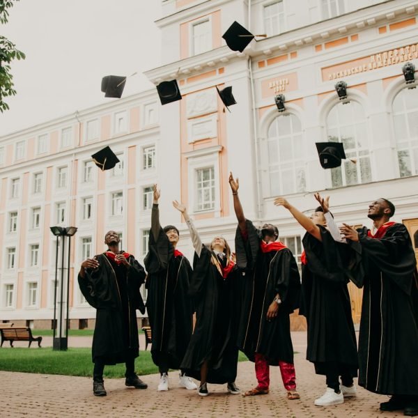 people in black academic dress standing on green grass field during daytime