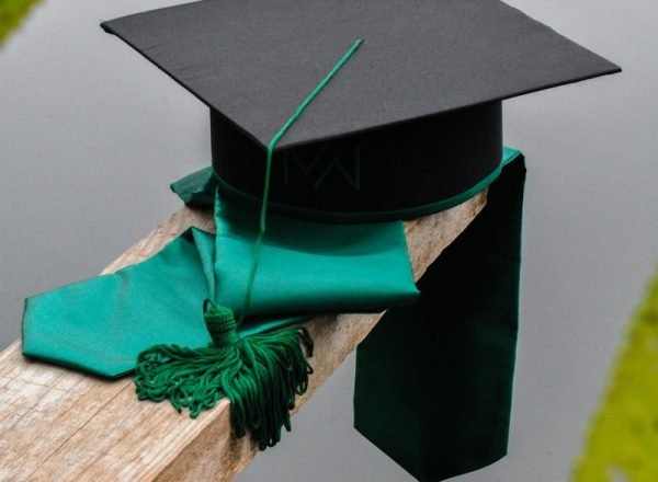 a graduation cap and a green tassel on a piece of wood